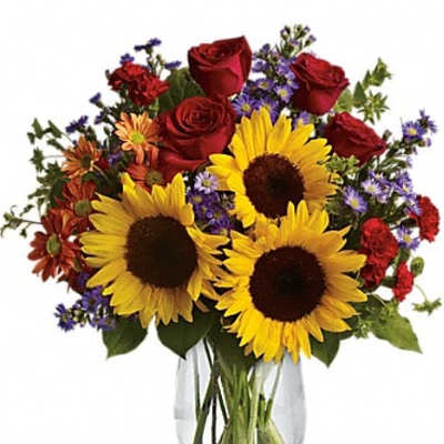 Bouquet of red roses and sunflowers in a clear glass vase