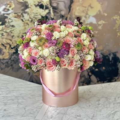 Round bouquet of pink, white, and purple roses in a pink hat box