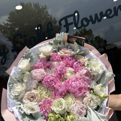 Pink and white bouquet with roses and peonies wrapped in pale paper