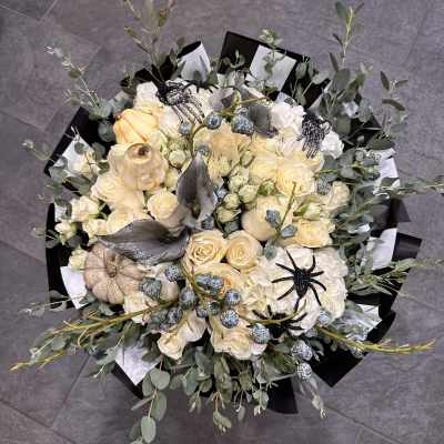 Cream rose bouquet with white hydrangeas, pumpkins, and black spider decorations