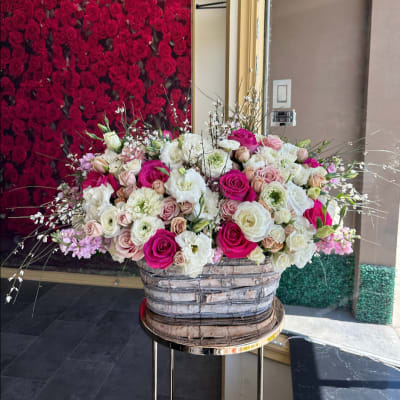 Large mixed rose arrangement in a woven basket on a stand