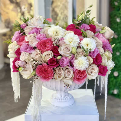Large pink and white rose arrangement in a white pedestal vase