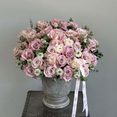 Pink rose bouquet in a gray urn vase with ribbon tails