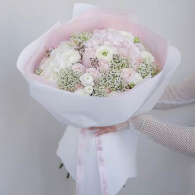 Bouquet of pale pink and white flowers wrapped in pink paper