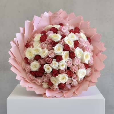 Bouquet of pink, red, and white roses wrapped in pink paper