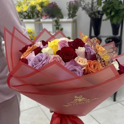 Bouquet of multicolored roses wrapped in pink paper with a red ribbon