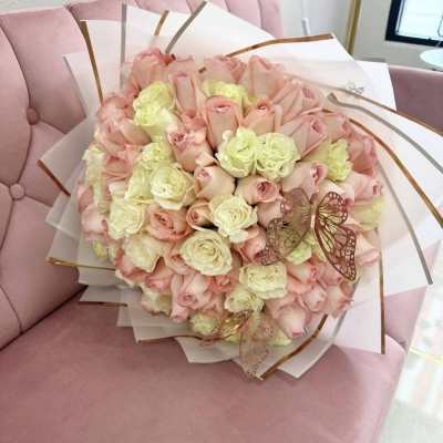 Bouquet of pale pink and cream roses wrapped in white paper