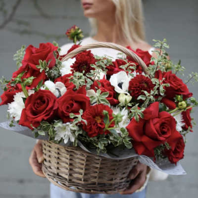 Basket of red roses and white flowers held by a woman