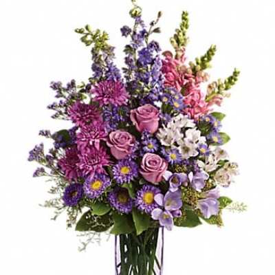 Purple and pink mixed flower arrangement in a clear glass vase