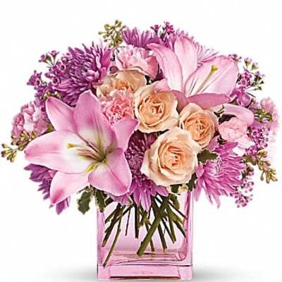 Pink and peach flowers arranged in a pink glass vase