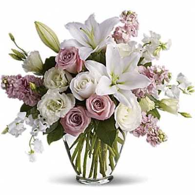 Pink and white roses with lilies in a clear glass vase