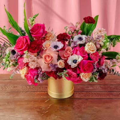Mixed pink and red floral arrangement in a gold vase