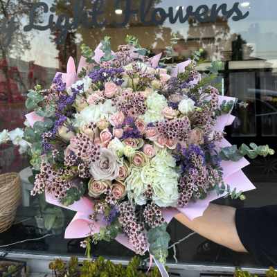 Large bouquet of pink and white roses with purple accents and eucalyptus