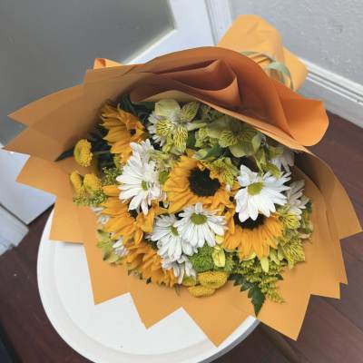 Bouquet of sunflowers and white daisies wrapped in orange paper