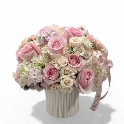 Pink and white rose bouquet in a ribbed cream vase