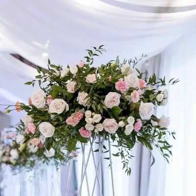Large floral arrangement of pale pink and white roses on a tall stand