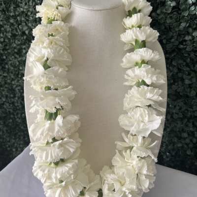 White carnation lei draped over a beige display bust