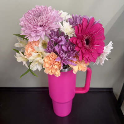 Bouquet of pink, purple, white, and peach flowers in a bright pink tumbler