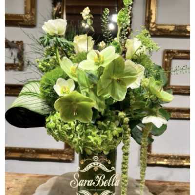 Green floral arrangement in a dark glass vase
