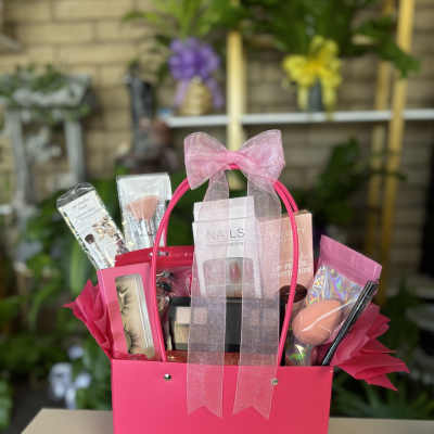 Pink gift basket with makeup items and a sheer bow