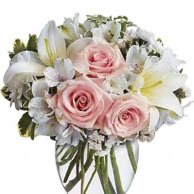 Pink roses and white lilies arranged in a clear glass vase