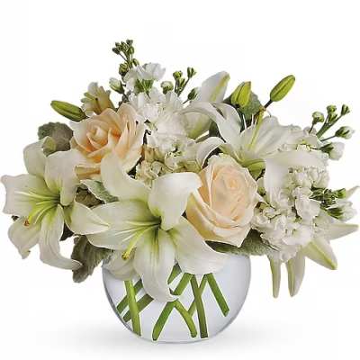 White lilies and pale roses arranged in a clear glass vase