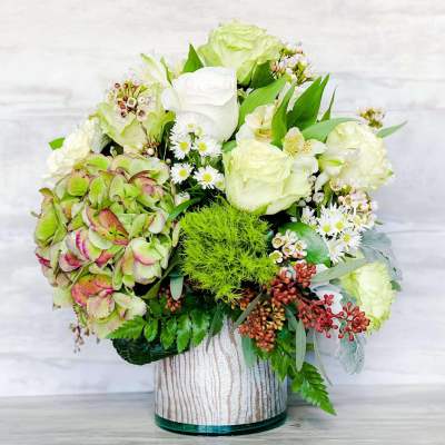 White and pale green floral arrangement in a glass vase