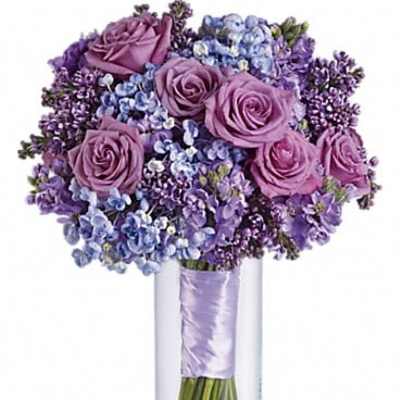 Purple roses and blue-purple flowers in a clear glass vase