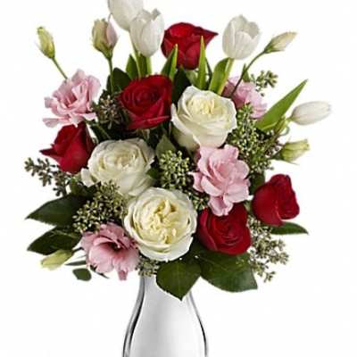 Bouquet of red and white roses with pink flowers in a clear glass vase