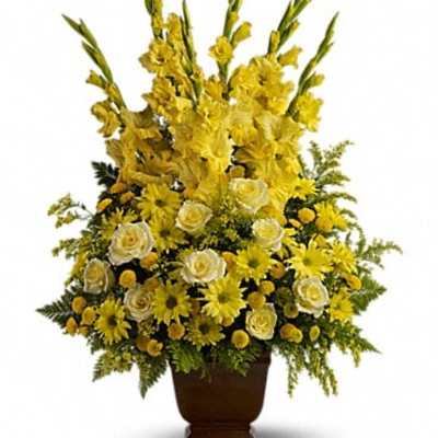 Tall yellow floral arrangement in a brown urn vase
