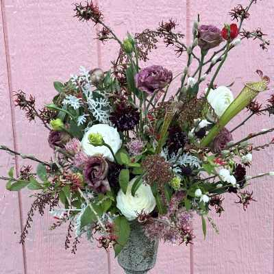 Mixed bouquet in a gray pedestal vase with white and purple blooms