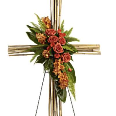 Floral cross on a stand with orange roses and greenery