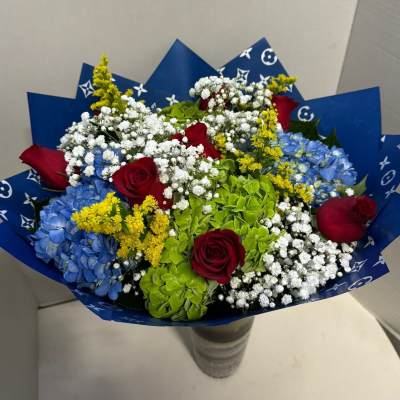 Bouquet of red roses, blue hydrangeas, and white baby's breath in blue wrap