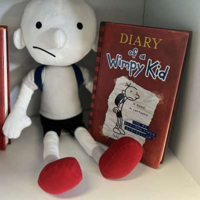 Plush doll sitting beside a Diary of a Wimpy Kid book