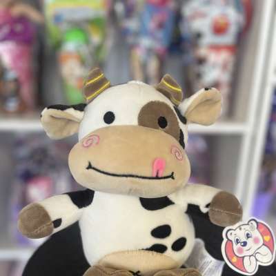 Plush cow toy sitting on a black round display table