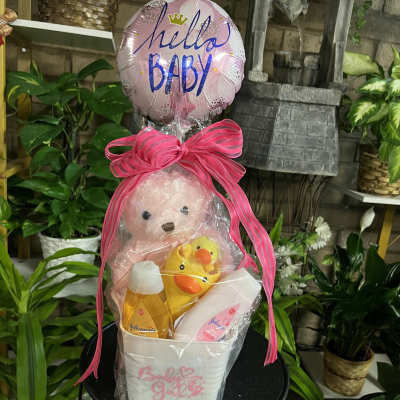 Baby gift basket with a teddy bear, rubber duck, and pink balloon