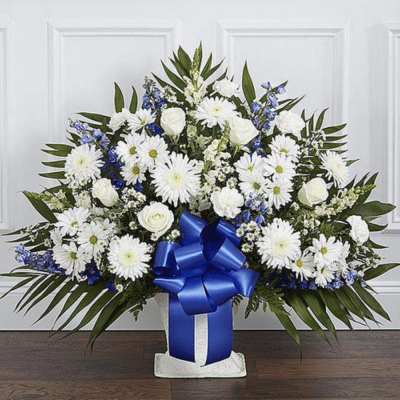 White and blue floral arrangement in a vase with a large blue ribbon