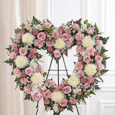 Heart-shaped floral wreath of pink and white flowers on a stand