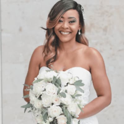 Bride holding a cascading bouquet of white roses and greenery