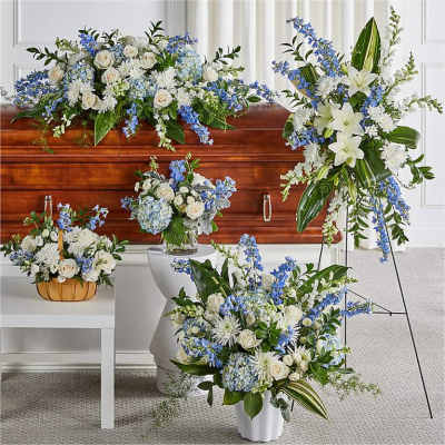 White and blue funeral flower arrangements around a casket