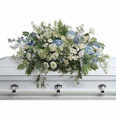 White and blue floral casket spray on a white casket