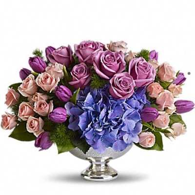 Lavender roses and blue hydrangeas in a silver pedestal bowl