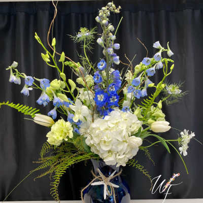 Tall blue and white floral arrangement in a dark vase