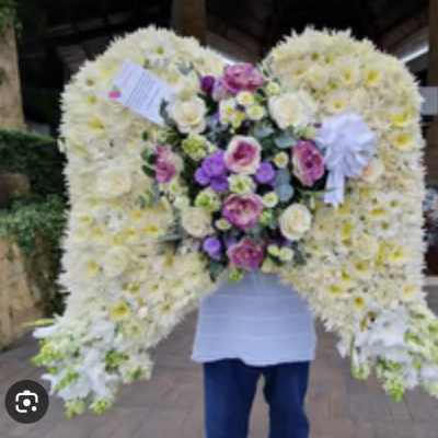 Large floral tribute shaped like angel wings with white and purple flowers
