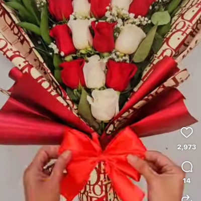 Bouquet of red and white roses wrapped in red paper with a bow.