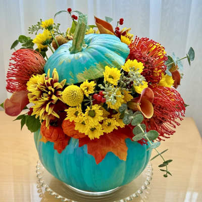 Bright autumn bouquet arranged around a painted blue pumpkin centerpiece