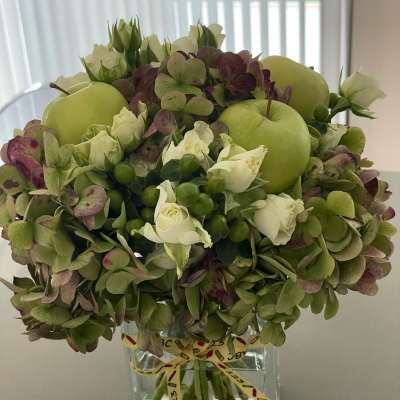 Green hydrangea and white rose arrangement in a clear square vase