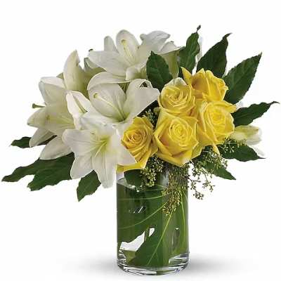 White lilies and yellow roses in a clear glass vase