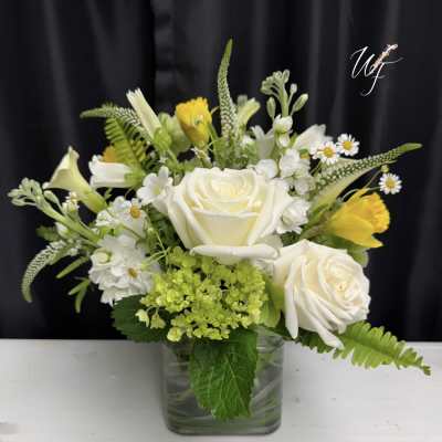 White roses and yellow flowers in a clear glass vase