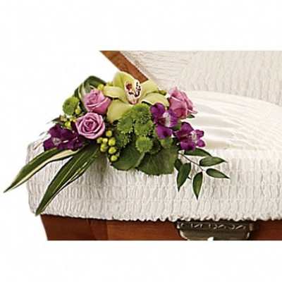 Pink and purple floral spray on a white casket